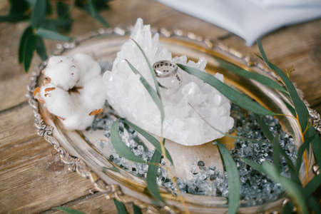 Silver plate with two wedding ring and white crystal on wood background.の写真素材