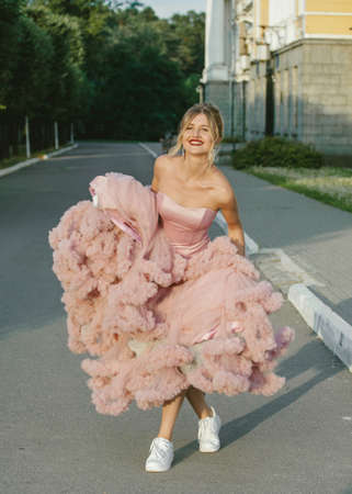 Bridal Fashion. Portrait of young beautiful modern bride in sneakers, with stylish make-up and and hairdo in wedding pink dress.の写真素材