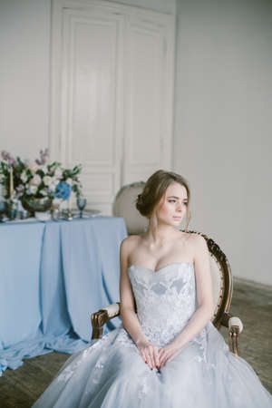 Portrait of young beautiful modern bride in grey lace dress sitting in a sofa.の写真素材