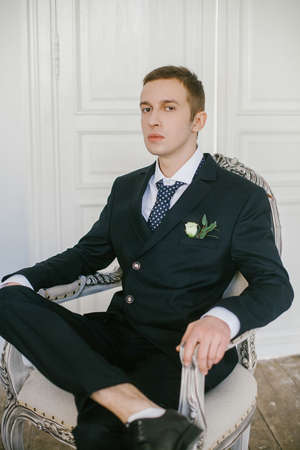Portrait of beautiful and stylish modern young bridegroom in suit decorated flowers boutonniere.の写真素材