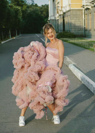 Bridal Fashion. Portrait of young beautiful modern bride in sneakers, with stylish make-up and and hairdo in wedding pink dress.の写真素材