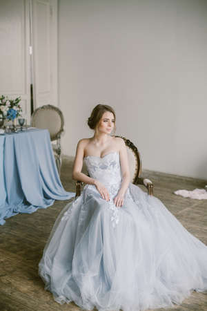 Portrait of young beautiful modern bride in grey lace dress sitting in a sofa.の写真素材