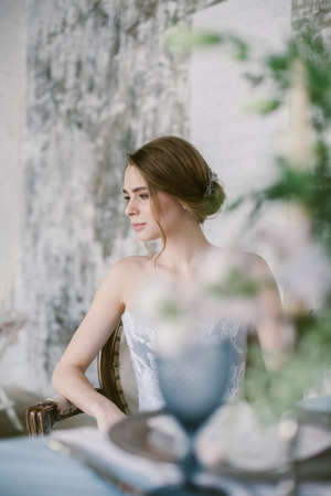Portrait of young beautiful modern bride in grey lace dress sitting in a sofa.の写真素材
