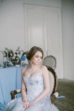 Portrait of young beautiful modern bride in grey lace dress sitting in a sofa.の写真素材