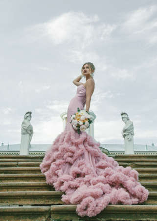 Bridal Fashion. Portrait of young beautiful modern bride with stylish make-up and and hairdo in mermaid style wedding pink dress.の写真素材