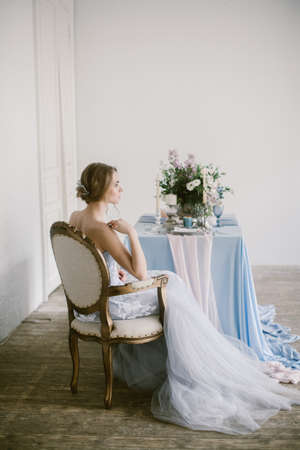 Portrait of young beautiful modern bride in grey lace dress sitting in a sofa.の写真素材