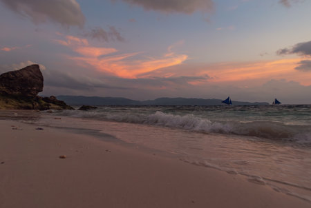 Calm evening on a sandy beach with boats sailing in the distance. Boracay, Philippines.の写真素材