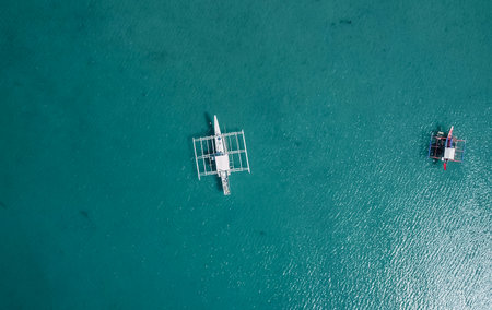 Aerial drone view of boats anchored in the bay with clear and turquoise water on sunny day. Boats in the tropical lagoon. Tropical landscape. El Nidoの写真素材