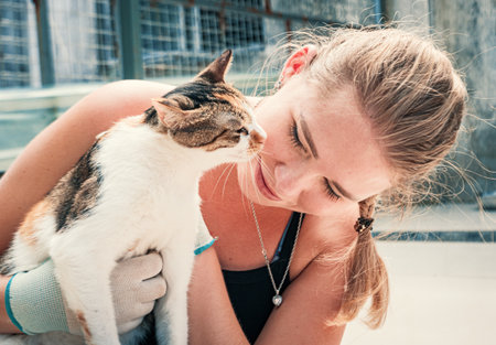 Close-up of female volunteer hugs cat in shelter. Shelter for animals conceptの写真素材