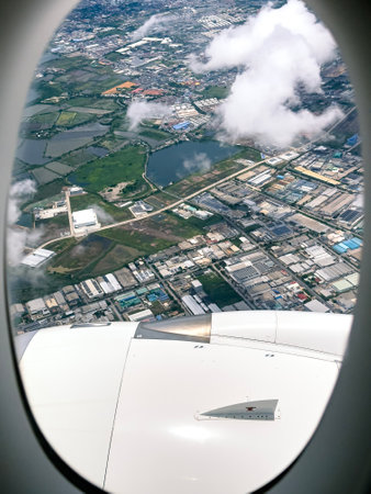 Scenic aerial view of urban landscape with clouds and water from airplane window during daytime journeyの写真素材