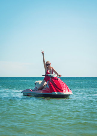 Woman enjoying a sunny day on a jet ski in clear blue ocean waters near a tropical beachの写真素材