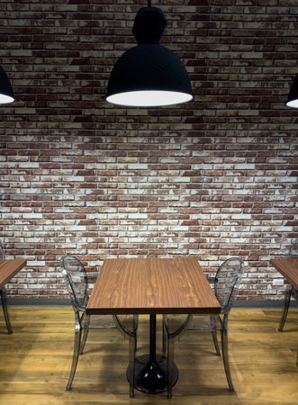 Comfortable library setting with wooden tables and modern chairs against a brick wallの写真素材