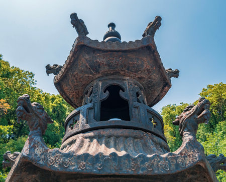 Ancient lantern stands tall amidst lush greenery in a serene outdoor setting under a clear blue skyの写真素材