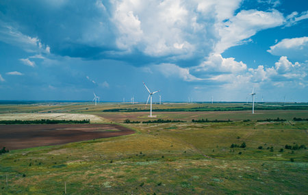 Wind turbines generate renewable energy in vast open landscape under a cloudy skyの写真素材
