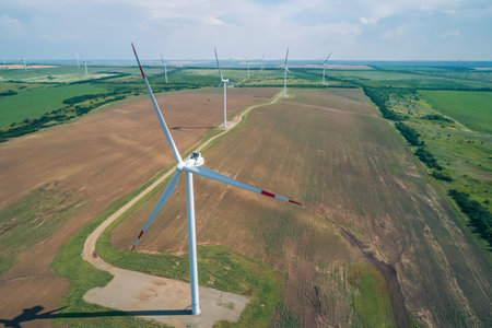 A row of large wind turbines stands tall in a vast, open field, showcasing renewable energy production.の写真素材