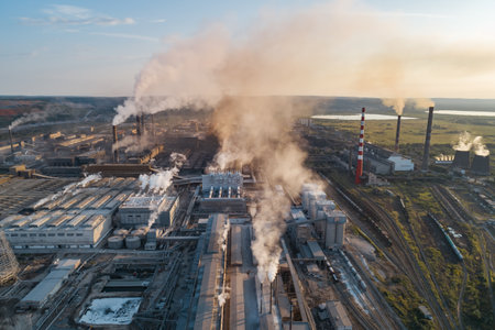 Industrial pollution causes environmental degradation in a large manufacturing facility with smoke and emissions during daytimeの写真素材