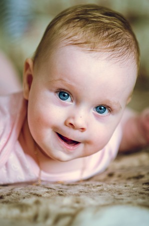 Portrait of a 7 month cute baby girl and lying down on her stomachの写真素材