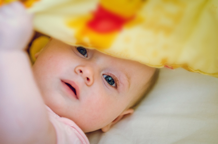 baby girl laying down in the bed hidingの写真素材