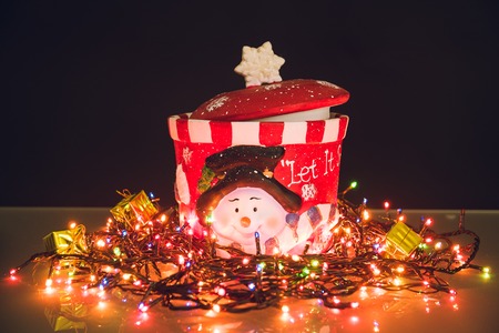 Snowman jar with lighted garland on black backgroundの写真素材