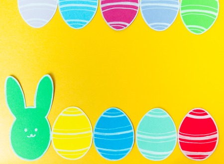 Close-up of colorful paper rabbit and paper eggs silhouette frames against canvas background