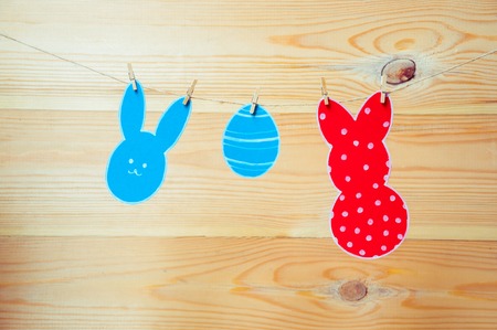 Close-up of colorful paper rabbits and paper egg silhouette frames hanging on a cord against wooden backgroundの写真素材