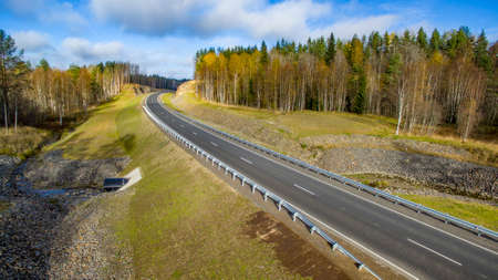 Aerial landscape view of empty rural road in beautiful autumn forestの写真素材