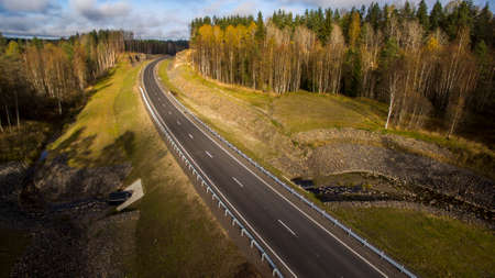 Aerial landscape view of empty rural road in beautiful autumn forestの写真素材