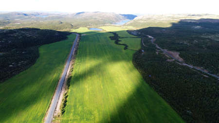 Aerial top view of a country road through a green rural fieldの写真素材