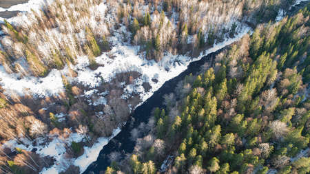 Aerial view of a river in the forest with snow along the banks.の写真素材