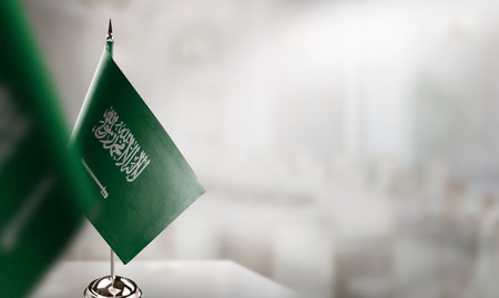 Small flags of the Saudi Arabia on an abstract blurry background.