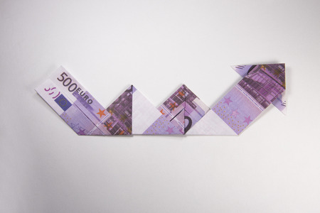 Arrow origami made of euro bills on a white backgroundの写真素材