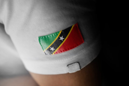 Patch of the national flag of the Saint Kitts and Nevis on a white t-shirtの写真素材