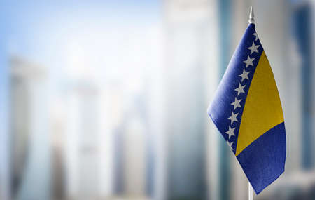 A small flag of Bosnia and Herzegovina on the background of a blurred backgroundの写真素材