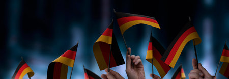 Germany flags in their hands on a blurred urban backgroundの写真素材