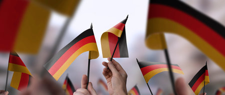 Germany flags in their hands on a blurred urban backgroundの写真素材