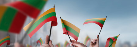 Lithuania flags in their hands on a blurred urban backgroundの写真素材