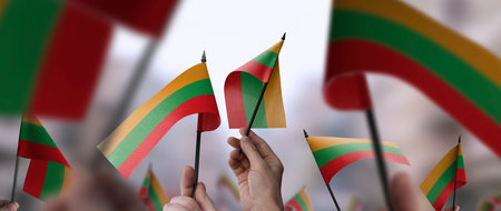 Lithuania flags in their hands on a blurred urban backgroundの写真素材