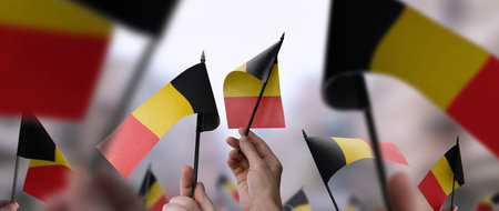 Belgium flags in their hands on a blurred urban backgroundの写真素材