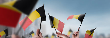 Belgium flags in their hands on a blurred urban backgroundの写真素材