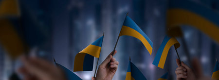 Ukraine flags in their hands on a blurred urban backgroundの写真素材