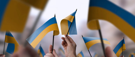 Ukraine flags in their hands on a blurred urban backgroundの写真素材