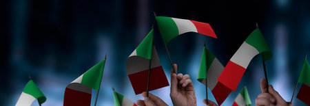 Italy flags in their hands on a blurred urban backgroundの写真素材