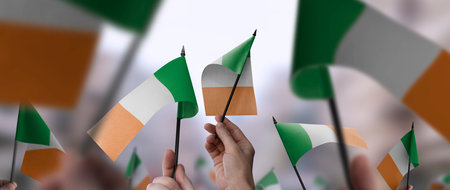Ireland flags in their hands on a blurred urban backgroundの写真素材