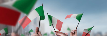 Italy flags in their hands on a blurred urban backgroundの写真素材