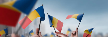 Chad flags in their hands on a blurred urban background. The photo illustration was created without the use of artificial intelligence, only using Photoshop.の写真素材
