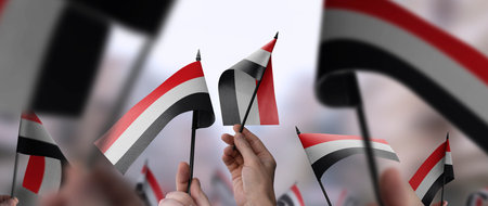 Yemen flags in their hands on a blurred urban background