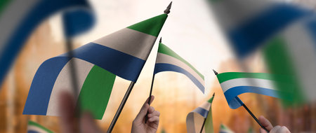 Sierra Leone flags in their hands on a blurred urban backgroundの写真素材