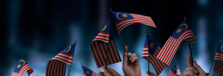 Malaysia flags in their hands on a blurred urban background