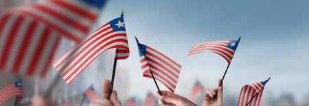 Liberia flags in their hands on a blurred urban background
