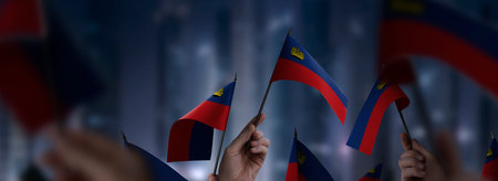 Liechtenstein flags in their hands on a blurred urban backgroundの写真素材